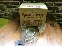 Box labeled '32 Piece Random Rose Homemaker Set' with three glass pieces displayed in front - a bowl, a plate, and a tall glass, showing the pattern and packaging