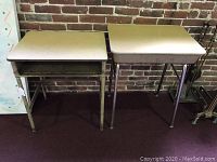 Photo showing two vintage Columbia Bicycles school desks side by side with metal frames and laminated wood tops, one desk with a tilt top and one fixed.