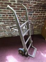 Side angled view of wooden hand truck dolly showing wood frame, wheels, and metal crossbar.