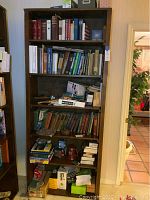 Front full view of tall wood bookcase filled with books and boxes to show shelving size and condition