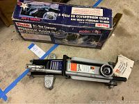 Hydraulic floor jack with original boxed packaging and visible handle and wheels.