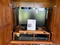 TV, DVD player, and VHS player inside wooden cabinet