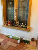 Bird houses, candle holders, and other decorative items arranged on wood window ledge and floor.