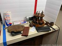 Full view of all pipes, stand, pipe cleaners, pouches, cleaning brush and pipe tool on a white table