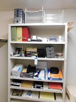 Photo showing white shelving unit with various folders, calculators, organizers, and office reference books.