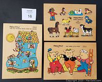 Three Fisher Price wooden puzzles laid side by side on black background: The Old Woman Who Lived in a Shoe (21 pieces), Farm Animals (9 pieces), and The Three Little Pigs (12 pieces). Puzzles show colorful thematic illustrations.