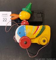 Side view of vintage wooden duck pull toy showing painted details and wheels.