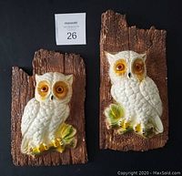 Front view of the pair of mid century chalkware owl wall plaques on brown panels.