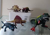 Five colourful dinosaur figures arranged around a white box, showing overall set and colour details.