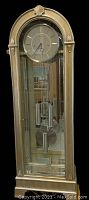 Full view of platinum-finish arched-top grandfather clock showing case, dial, weights and pendulum.