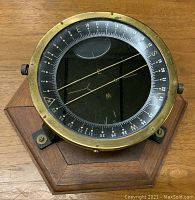 Top view showing compass dial with directional and degree markings, brass bezel, and glass with parallel wires inside.