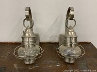 Front view of the pair of outdoor onion lanterns positioned upright on a surface showing metal frame and clear glass onion-shaped globes.