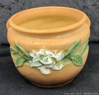 Front angled view of Roseville ceramic pot showing the floral motif and color gradient from orange to brown.
