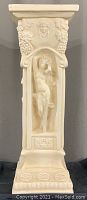 Front view of plaster column showing nude female figure with raised arm and classical grapevine motif above.
