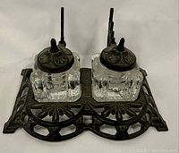 Top front angle view showing double glass ink wells set in detailed cast iron base with lids and finials.