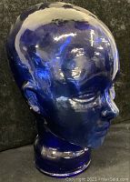 View from front left side showing facial details and glossy deep cobalt blue glass.