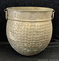 Front view showing the detailed embossed patterns and overall shape of the large brass basin with two side handles.