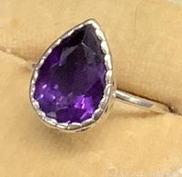 Close-up image of the pear-shaped faceted deep purple amethyst set in sterling silver with scalloped bezel.