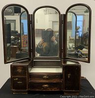 Front full view of antique Asian tabletop vanity with three folding mirrors open showing storage compartments and glass top.