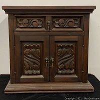 Front view of the chest showing the ornate carved drawer and double door cabinet.