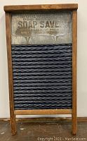 Front view of the antique washboard showing the blue porcelain enamel ridged washing surface with wooden frame and embossed metal top plate.