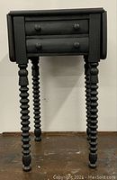 Front view with both leaves closed showing two drawers, round knobs and spool-turned legs