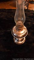 Side view of nickel plated coil oil lamp with glass chimney showing base, coil and wick