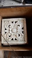 Single stone carved tile showing ornate floral motif and scrollwork
