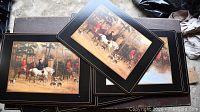 Photo of stacked rectangular place plates with black border and gold trim featuring an outdoor hunt scene with riders on horseback and hunting dogs.