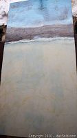 Single abstract canvas painting featuring muted colors including blue, gray and cream with textured brushwork, photographed outdoors on snow background.