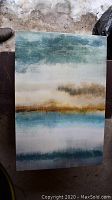 Photo of one rectangular canvas painting showing an abstract landscape with horizontal bands of green, beige, blue and brown tones.