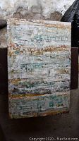 One of the three canvas paintings showing abstract textured art with colors white, grey, turquoise, brown, and yellow