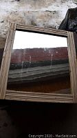 Rectangular glass mirror with a grooved wooden frame, photographed in an indoor setting with visible scratches on the glass surface.