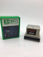 Front view of TD Bank Green Machine piggy bank and IBM 1983 promo desk caddy showing logos and details