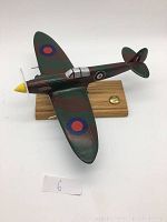 Front side view of the wooden RCAF bomber airplane model on stand showing camouflage paint and national insignia.