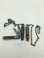 Vintage Barlow folding pocketknife with two folding blades and wood-grain style handle, closed and open position shown, paired with two ARKAY police whistles on chains.