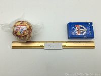 Photo showing the full lot with baseball in plastic wrap, deck of cards, and ruler for scale.