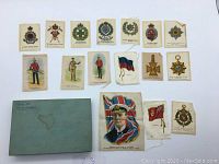 Top view of silk flags and military emblem cards laid out next to a green box labeled 'Box of Silk Flags'