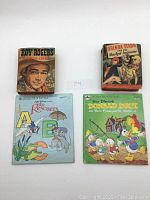 Four small vintage children's books arranged flat, front covers visible, showing titles and colorful illustrations.