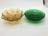 Two colored glass dishes: yellow amber with fish-scale and bubble texture, green with geometric bubble pattern, both approx 6 inch diameter.