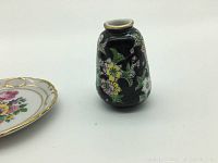 Close-up of the small blue ceramic vase with floral design on black background