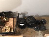 Photo showing two 10 lb dumbbells, one 35 lb dumbbell, one 20 lb dumbbell, and a basket containing assorted weight plates.