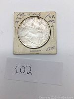 Overall photo of the 1899 French Indo China Piastre silver coin in protective holder with written notes.