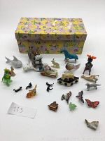 Full set of 22 assorted Easter-themed decorations and toys arranged in front of the box with lid closed, showing various animal figurines made of glass and plastic.
