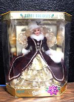 Front view of the sealed doll in original packaging wearing red velvet and gold lame dress with white fur trim