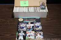 Box containing over 400 assorted football trading cards, a sealed Dan Marino mini figure on top, and the White's Guide to Collecting Figures magazine in front.