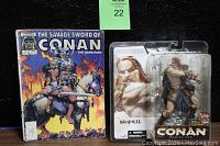 Comic book and sealed action figure shown together on black background with green auction tag