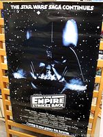 Front view of the original 1983 Star Wars The Empire Strikes Back poster featuring a black background with stars and a prominent Darth Vader image, laminated with glossy finish.