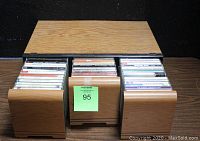 Front view of the wooden CD display case with the three pull-out compartments opened, revealing the CDs stored vertically inside.