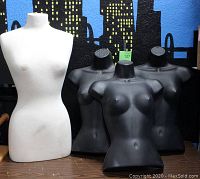 Front view of one large white pinnable sewing dress form mannequin and three black plastic female torso dress forms without heads or arms.